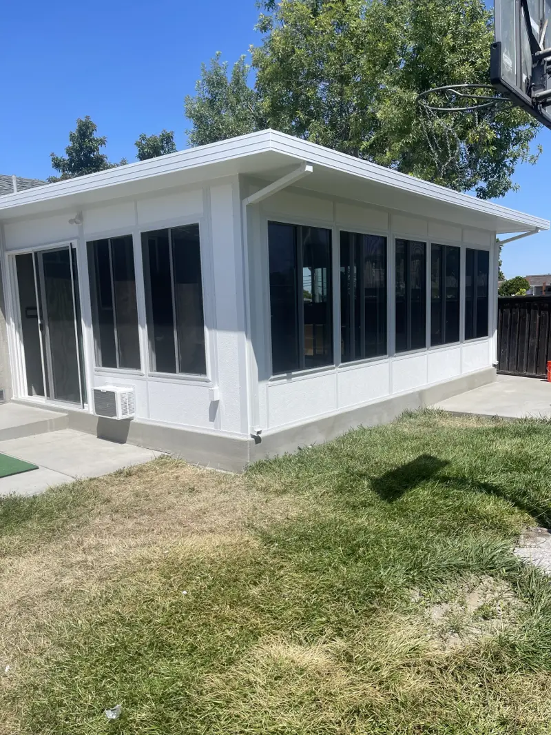 Large white sunroom with rows of tinted windows on a new concrete foundation