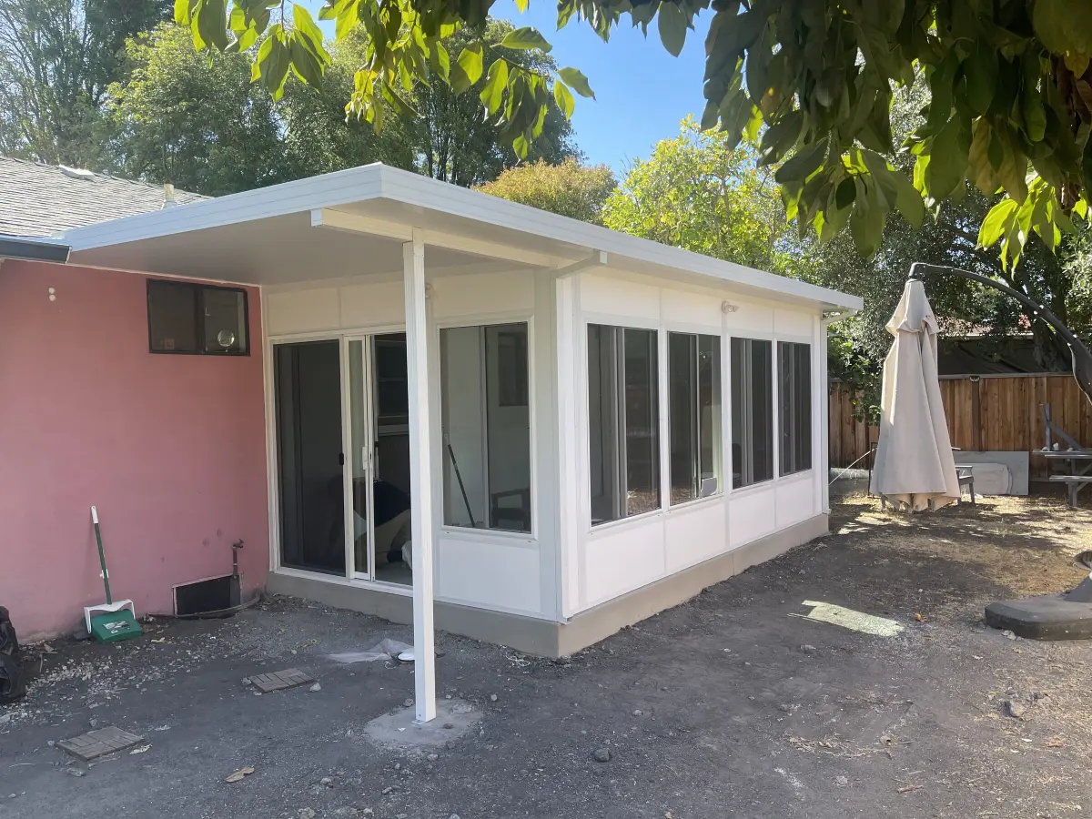 Sunroom addition with an extended patio cover and support post next to the house